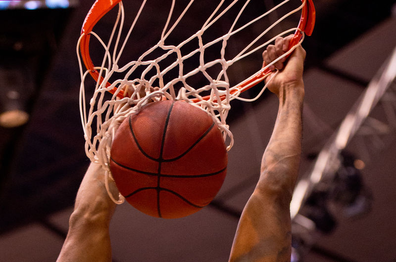 Un pallone da basket che entra nella retina, mani sul ferro.