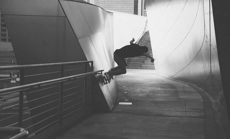 Uno skateboarder sulla parete curva in acciaio di un auditorium.